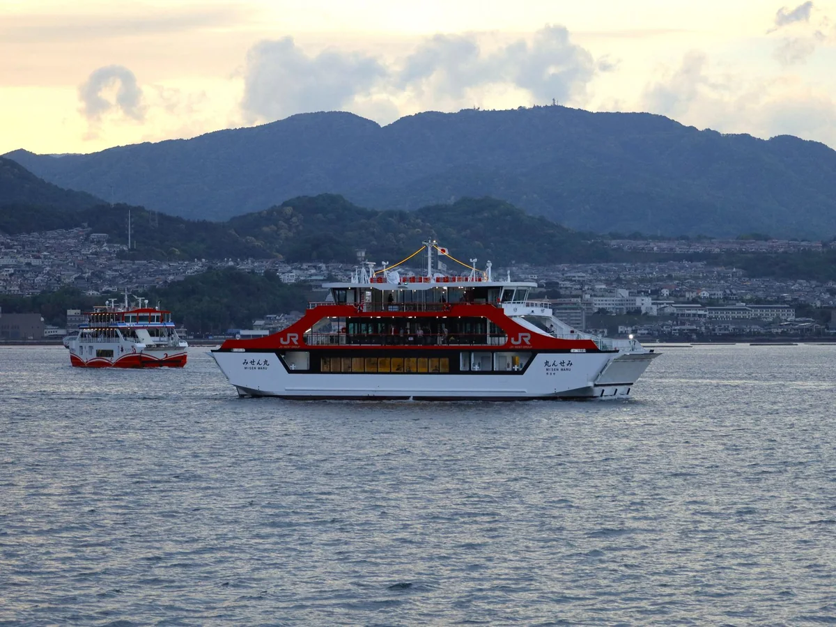Un traghetto JR che attraversa il Mare Interno di Seto verso Miyajima con le montagne sullo sfondo